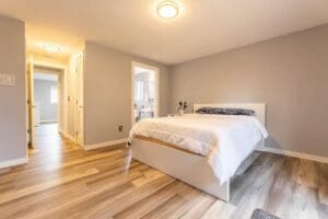 A bedroom with hard wood floors and white walls.