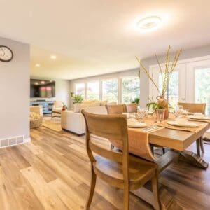 A dining room table with chairs and a clock on the wall.